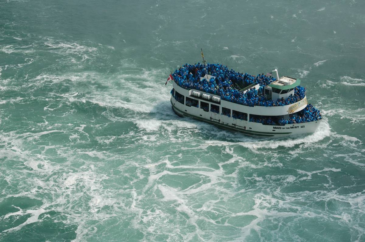 Maid of the Mist boat filled with passengers in blue ponchos near Niagara Falls.