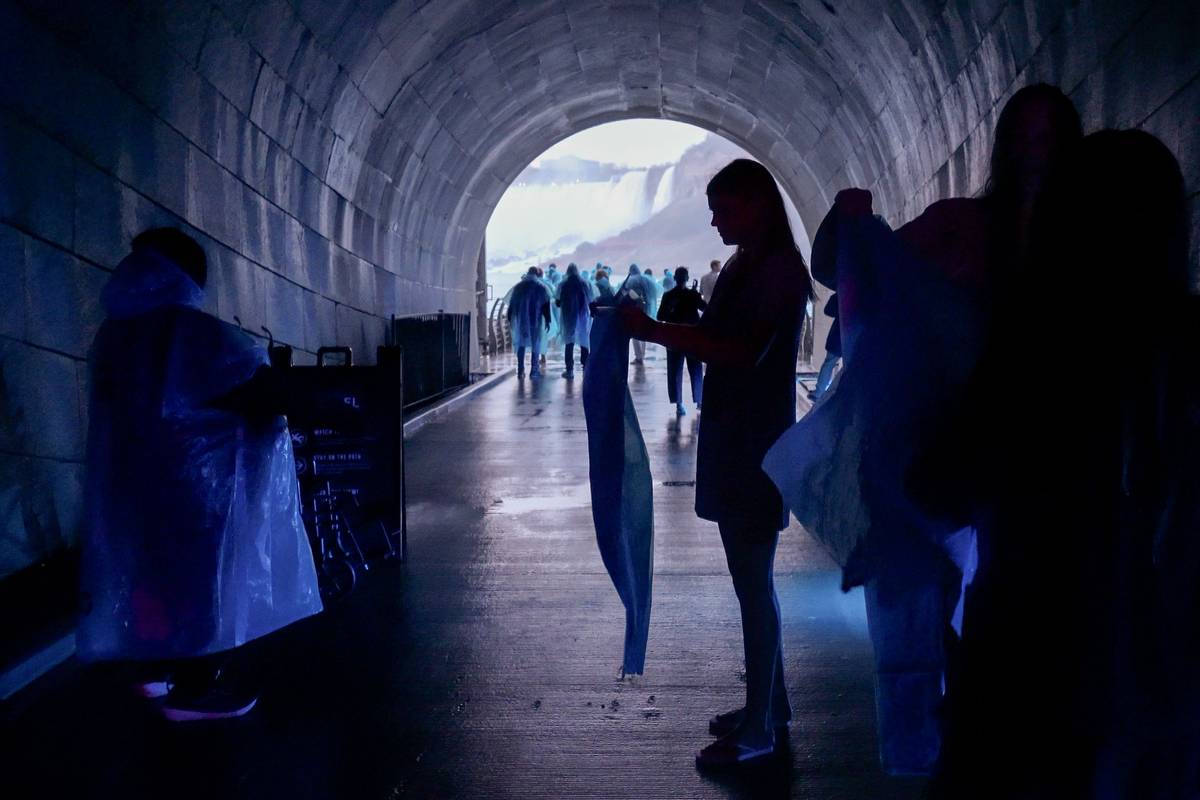 Visitors in ponchos entering tunnel with view of Niagara falls ahead.