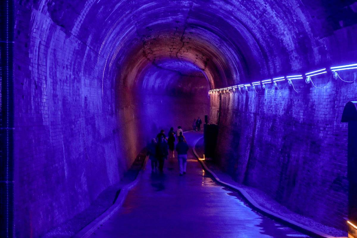 Visitors walking inside illuminated brick tunnel at Niagara Power Station.