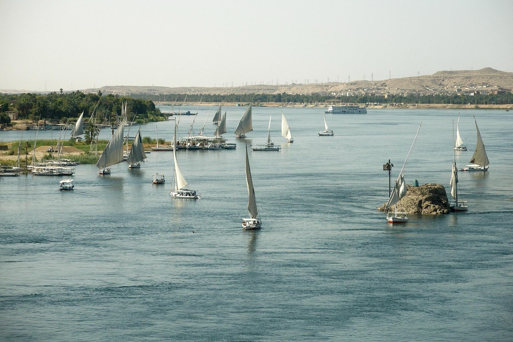 White felucca sails on the Nile at Aswan among granite rocks and green islands