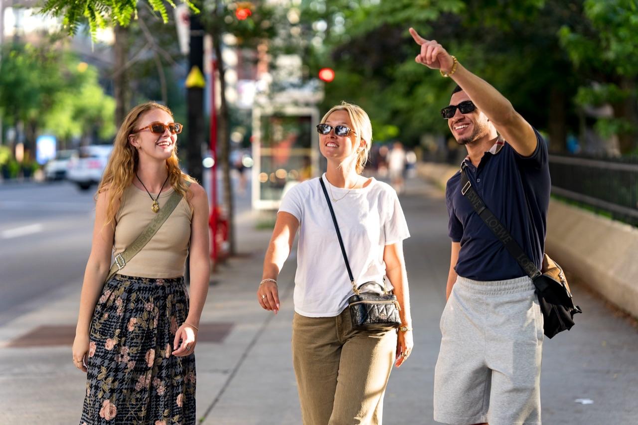 A See Sight Tours guide points out a landmark while walking with two guests on a Montréal street