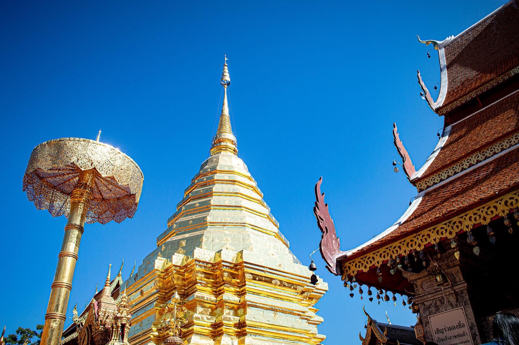 The golden chedi and golden parasol of Wat Phra That Doi Suthep against a deep blue sky