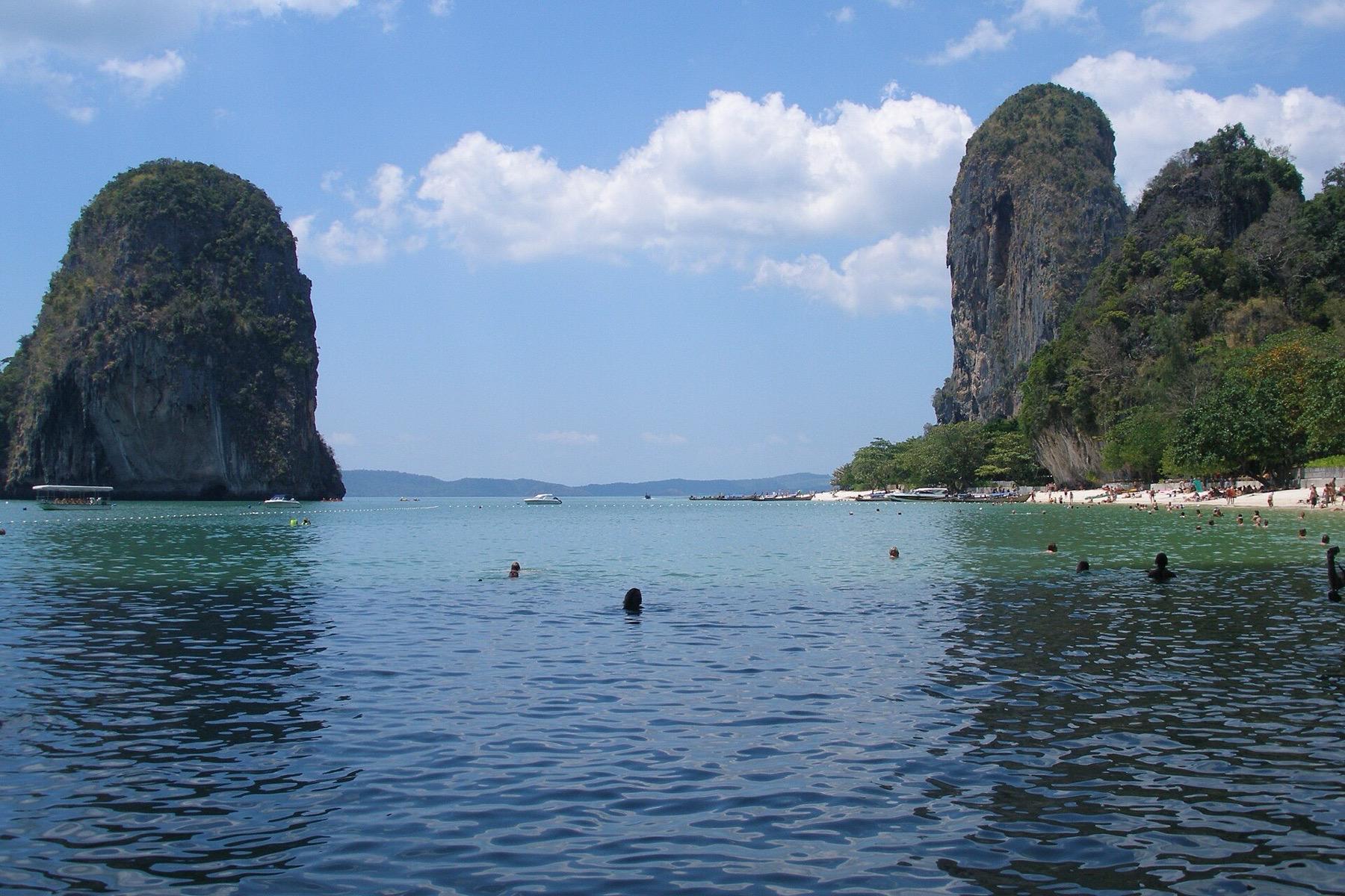 Clear shallow water and limestone cliffs at a beach on the Railay peninsula, with a rock island offshore