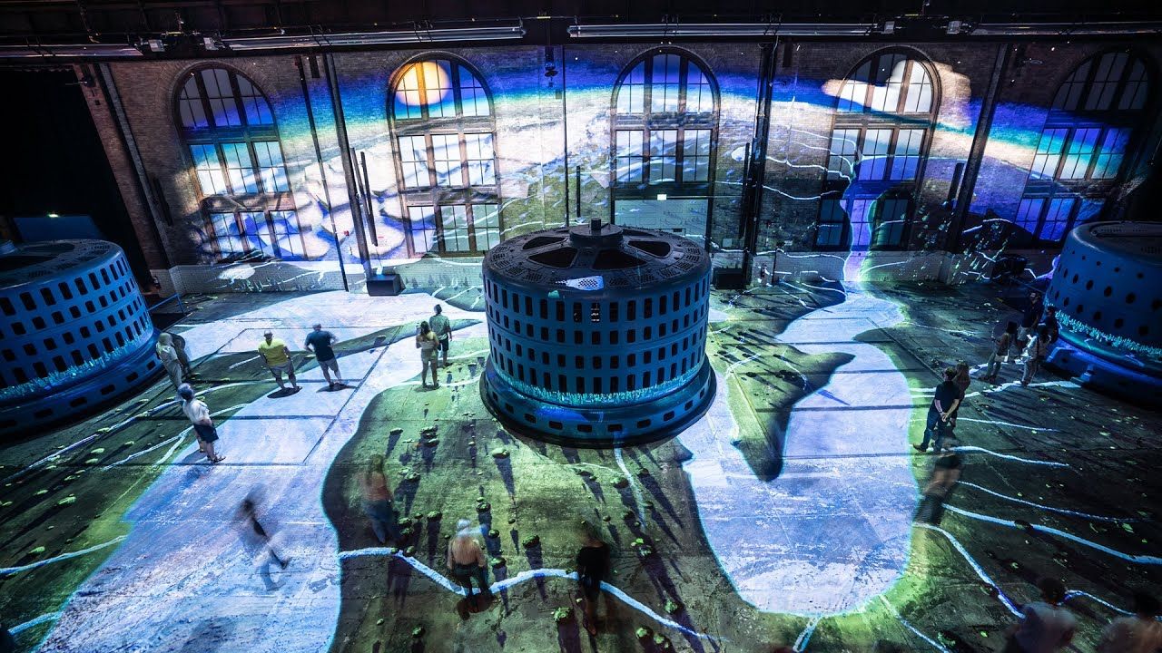 Visitors walking inside niagara parks power station with projections on floor and walls.