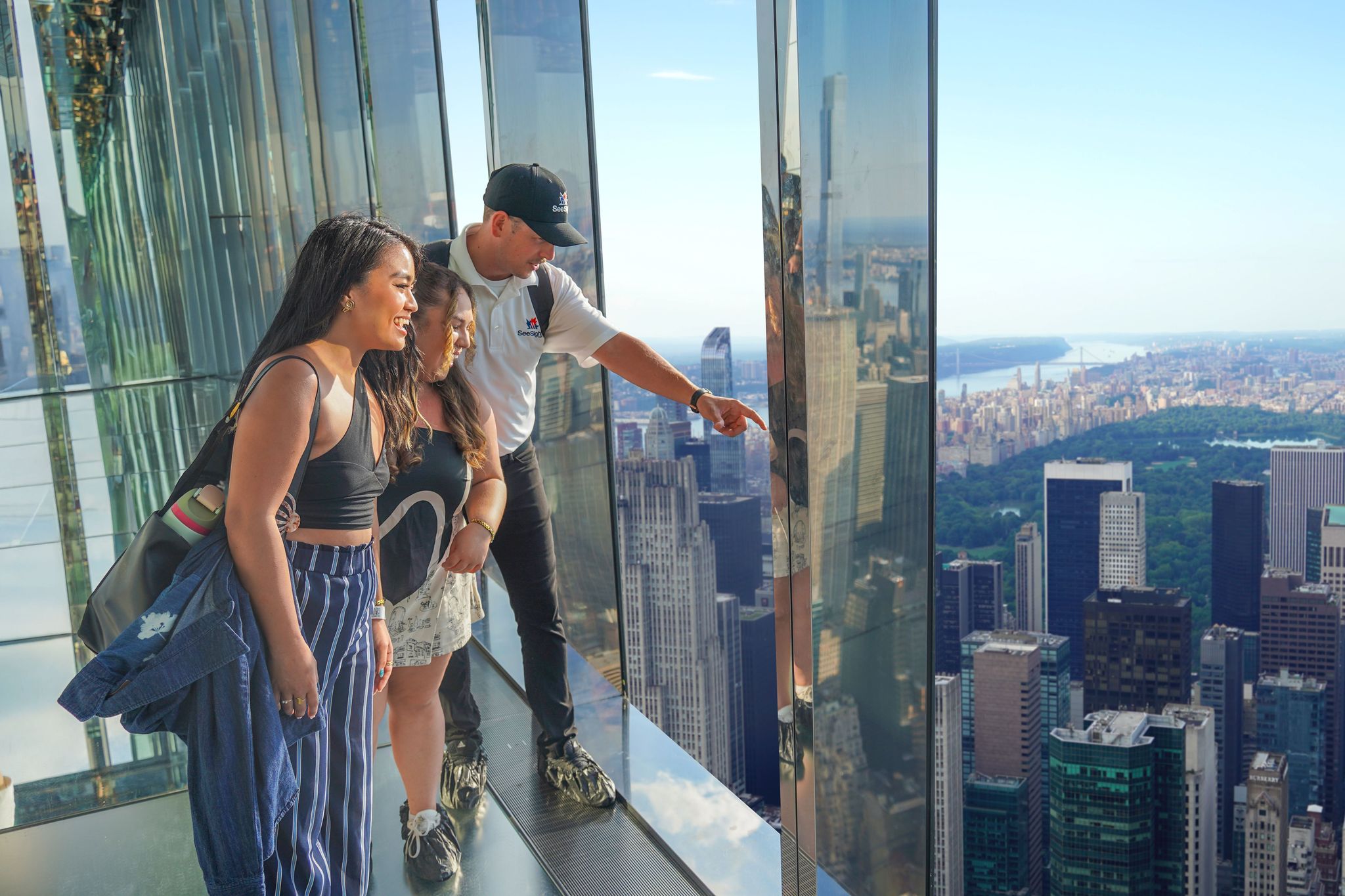 Tour guide with visitors at Summit One Vanderbilt overlooking NYC skyline.