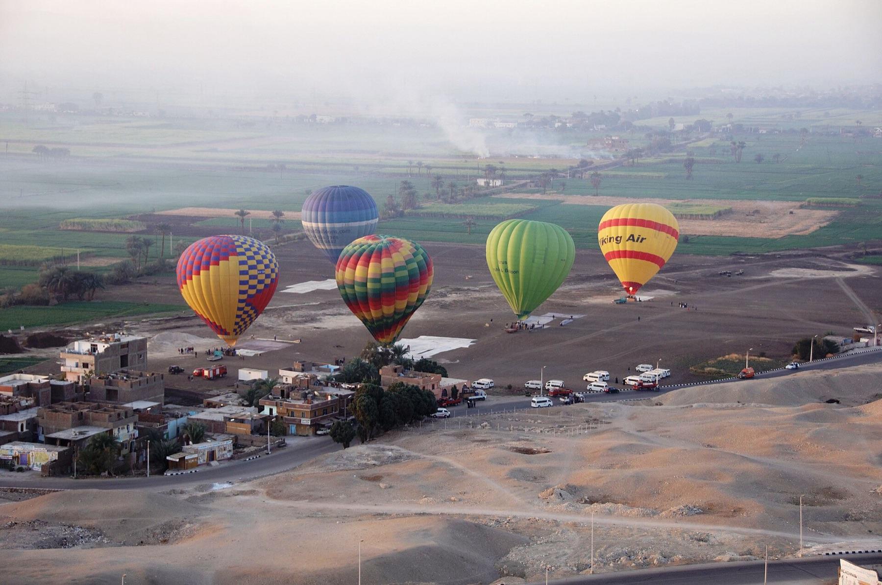 Hot-air balloons rising at dawn over the fields and villages of Luxor's West Bank