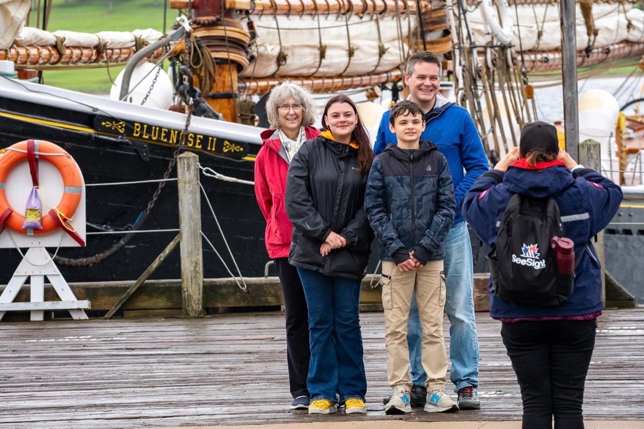 A See Sight Tours guide photographs a family in front of the Bluenose II in Halifax