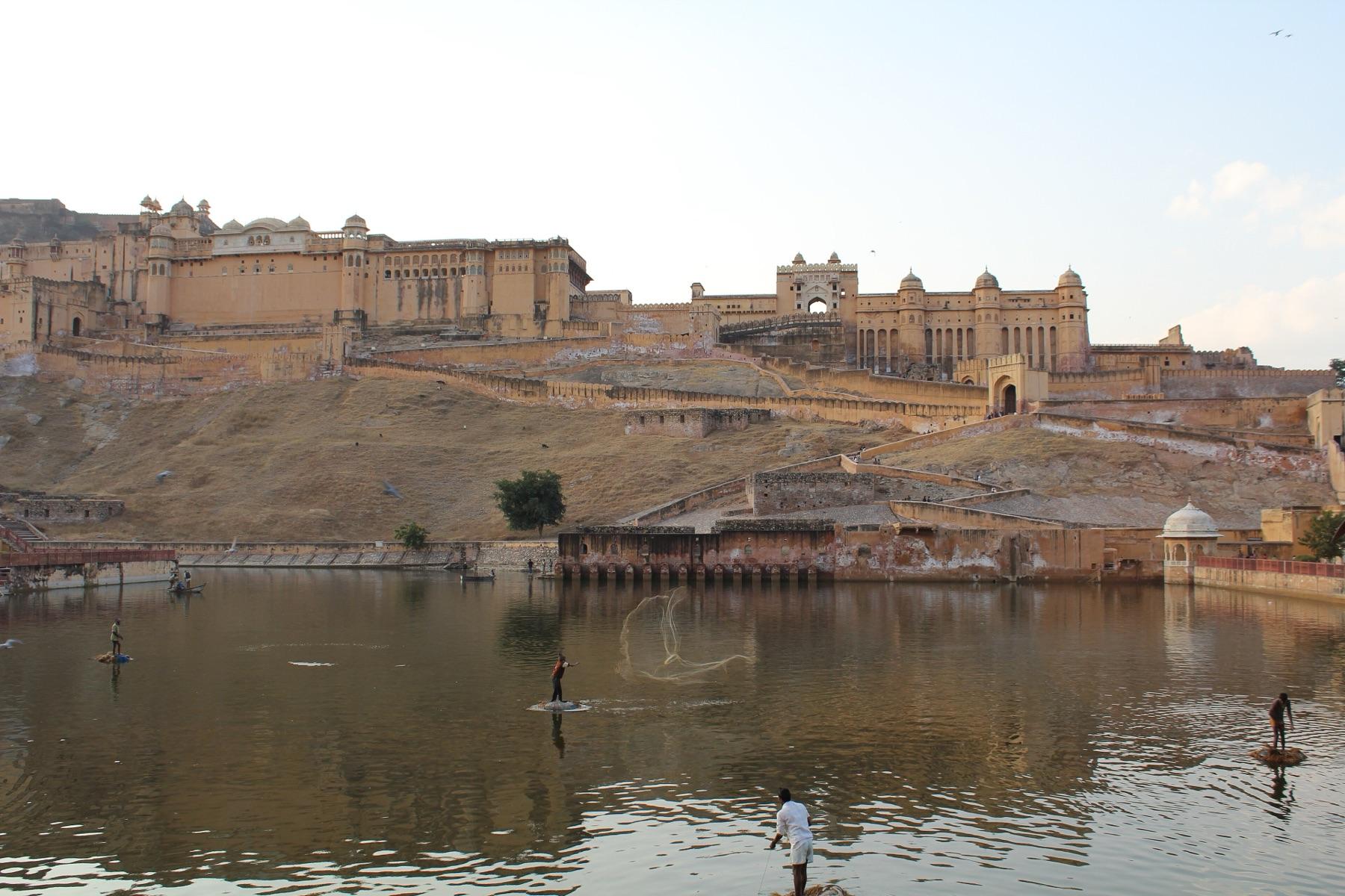 Amber Fort on its ridge above Maota Lake, with fishermen casting nets in the water below