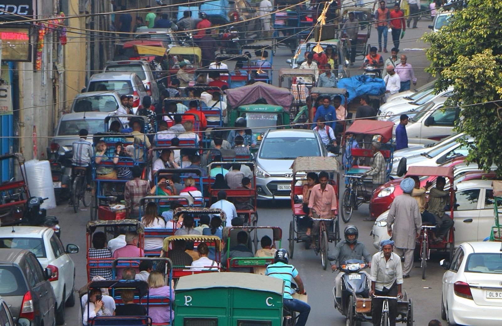 Cycle rickshaws, cars and people crowd a busy street in Chandni Chowk, Old Delhi