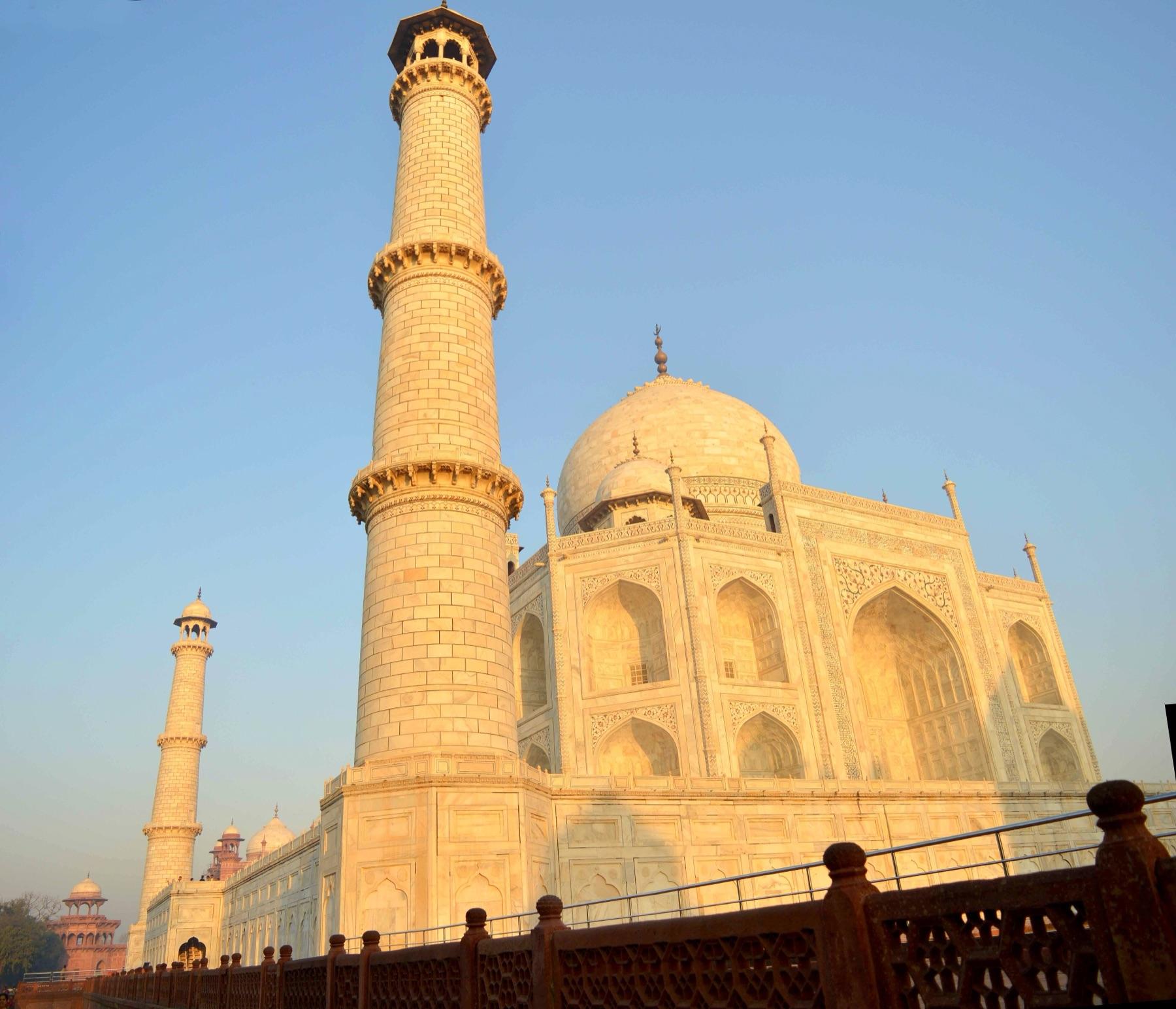 Early morning golden light on the white marble dome and a minaret of the Taj Mahal