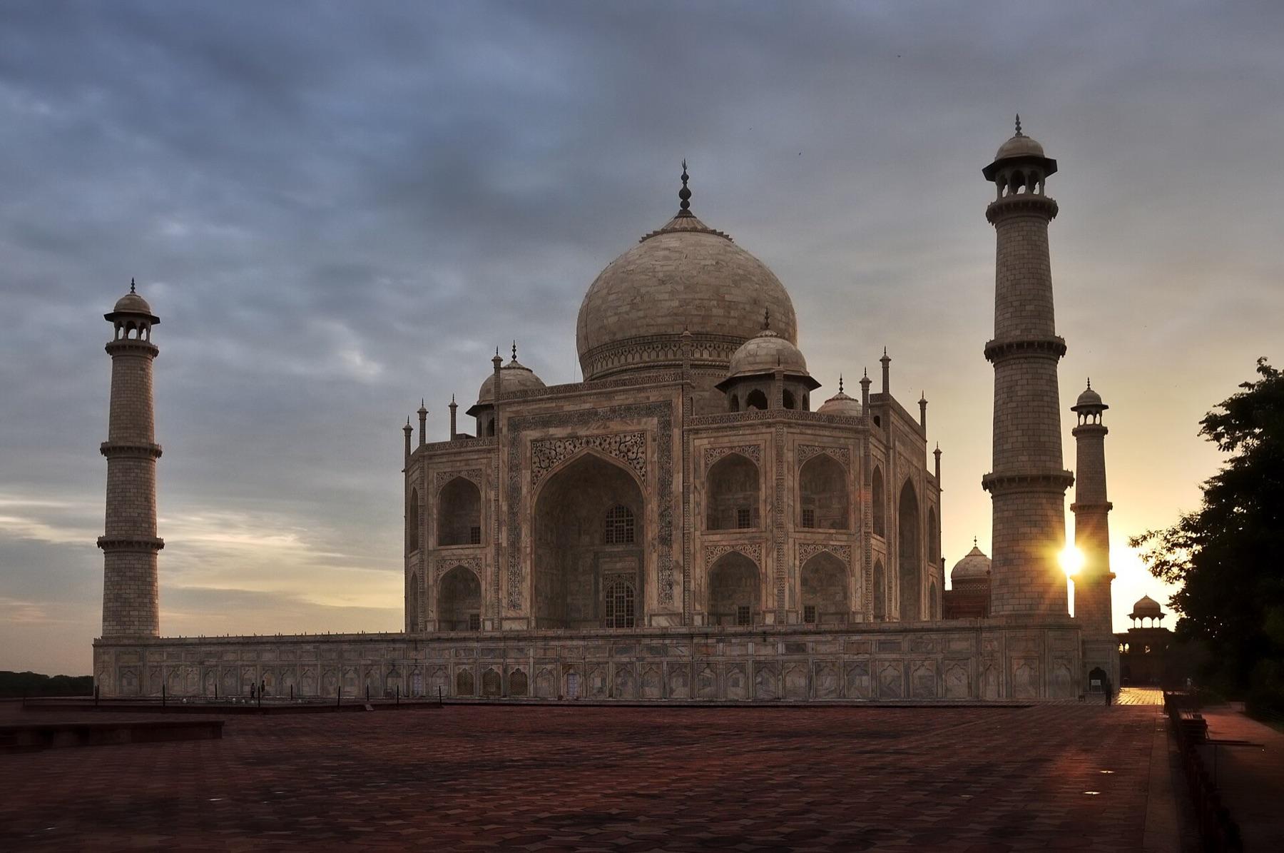 The Taj Mahal and its minarets at sunrise, with the sun rising beside the tomb