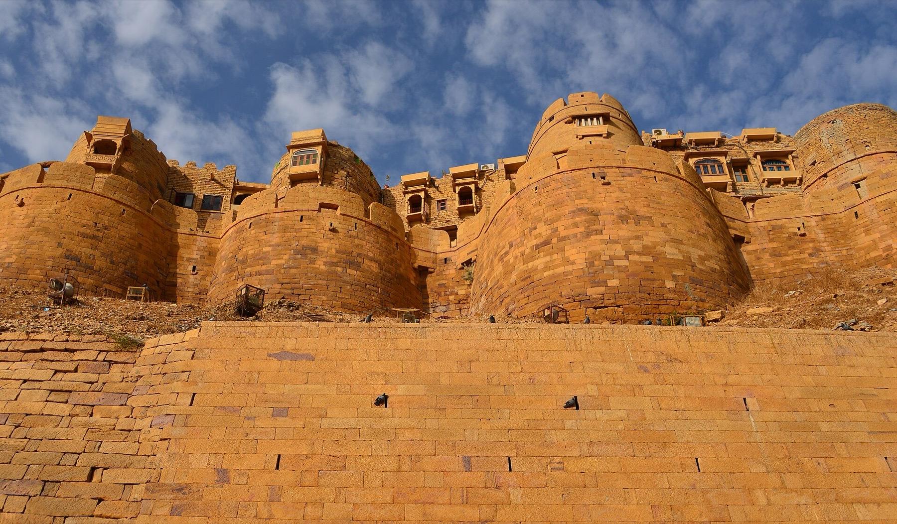 The round golden sandstone bastions of Jaisalmer Fort under a blue sky