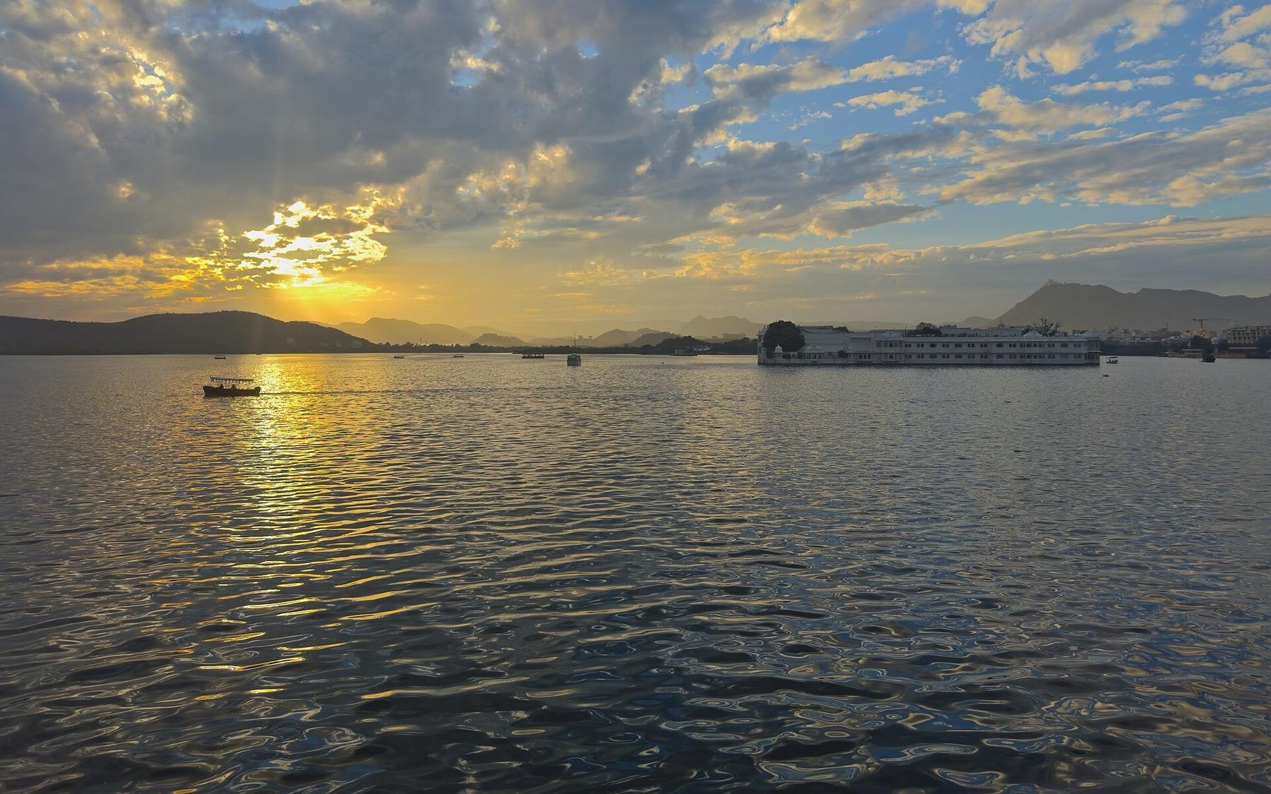 The sun setting over Lake Pichola in Udaipur, with the Aravalli hills on the far shore