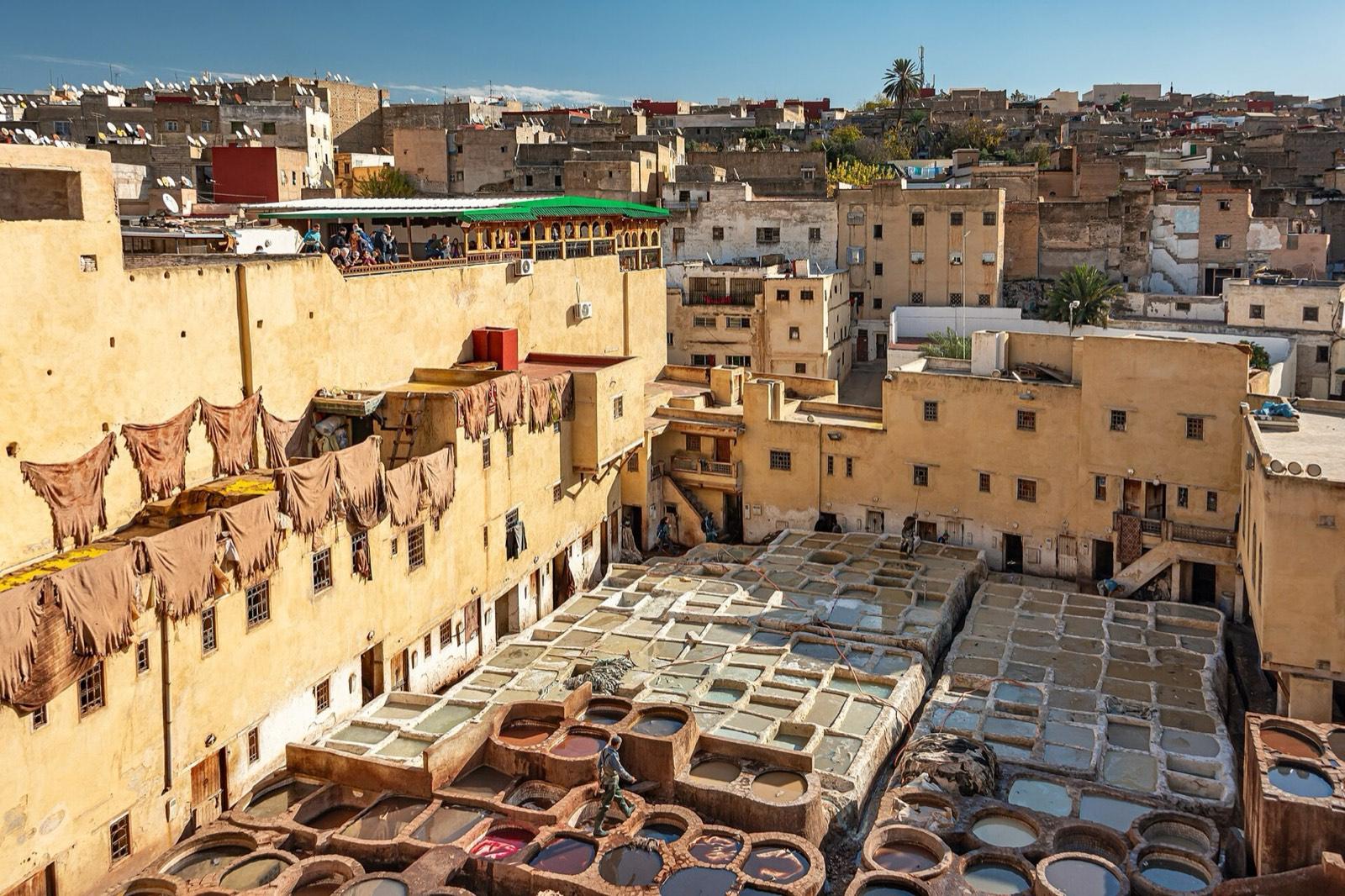 Stone vats of dye and white lime at the Chouara tannery in Fes, with hides drying on the walls around them