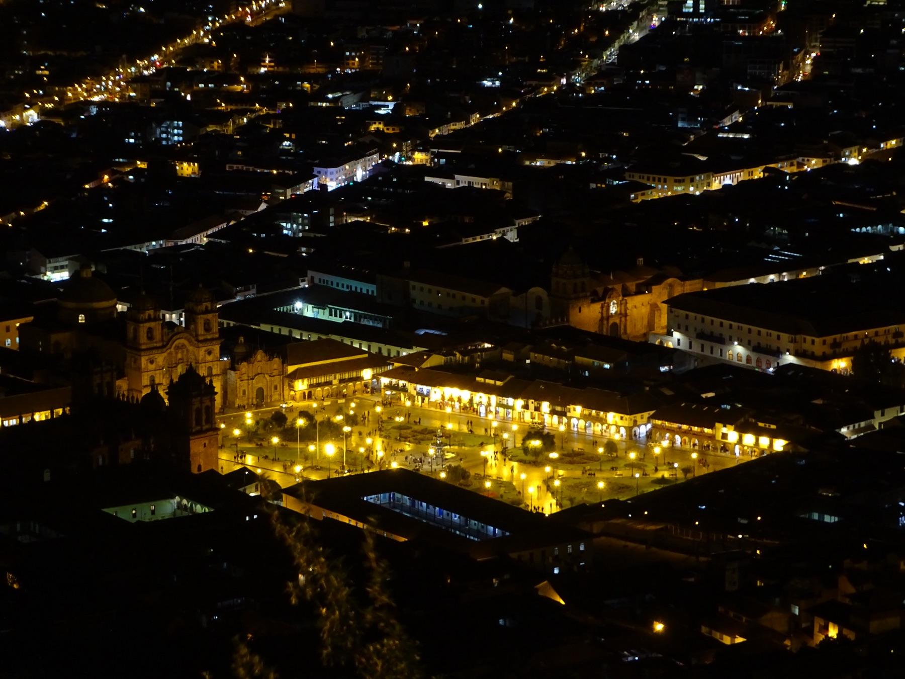 Cusco's Plaza de Armas lit up at night, seen from the hillside above the city