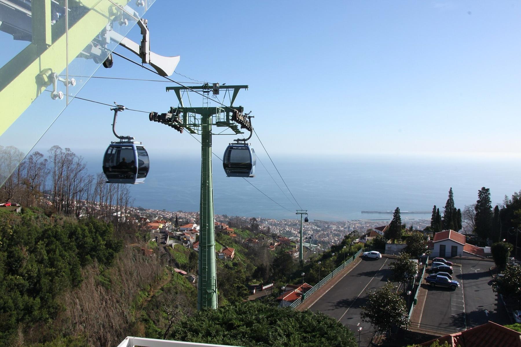 Cable car cabins climb from Funchal towards Monte, with the city and the Atlantic below