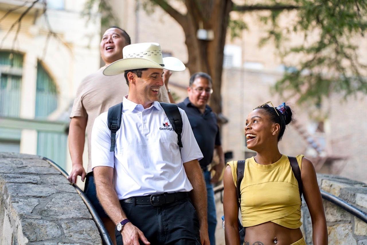 A See Sight Tours guide in a cowboy hat laughing with guests on a walking tour in San Antonio