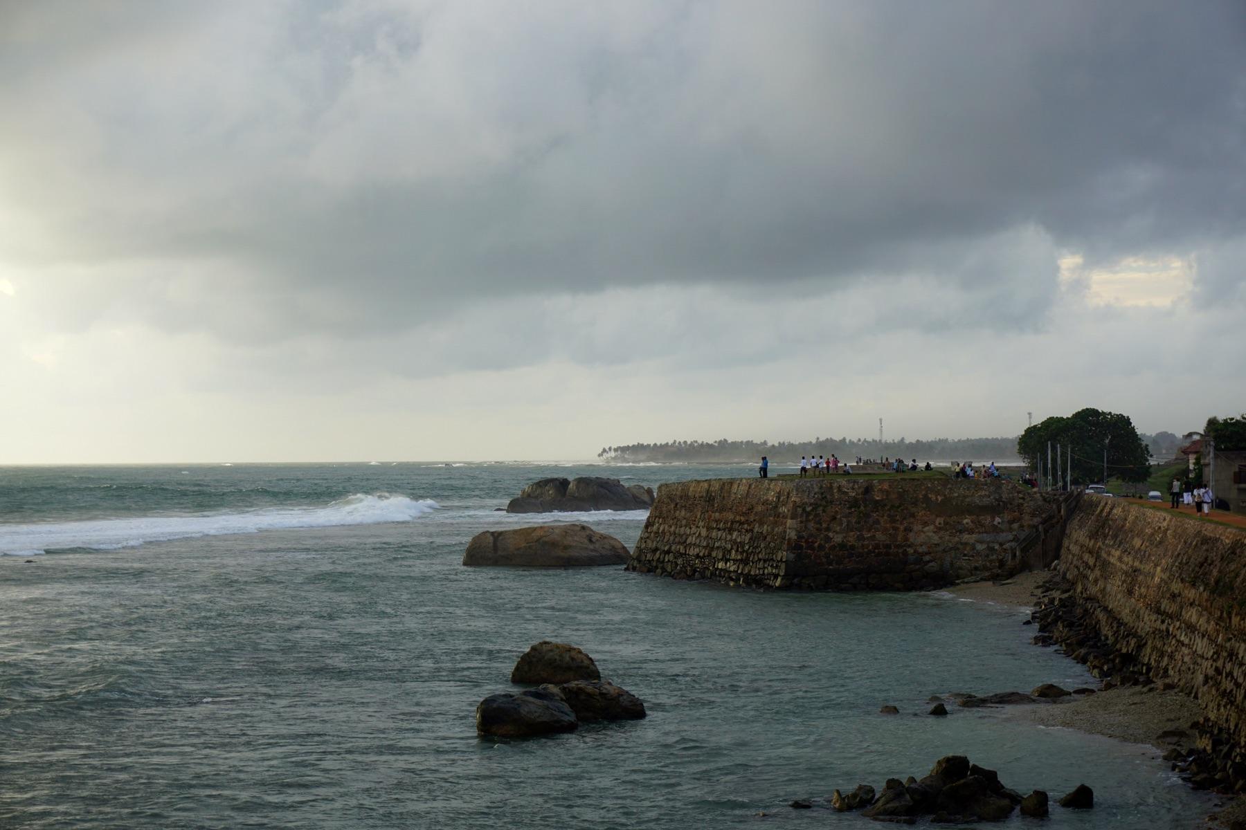 The sea wall and a bastion of Galle Fort in the evening, with waves on the rocks below