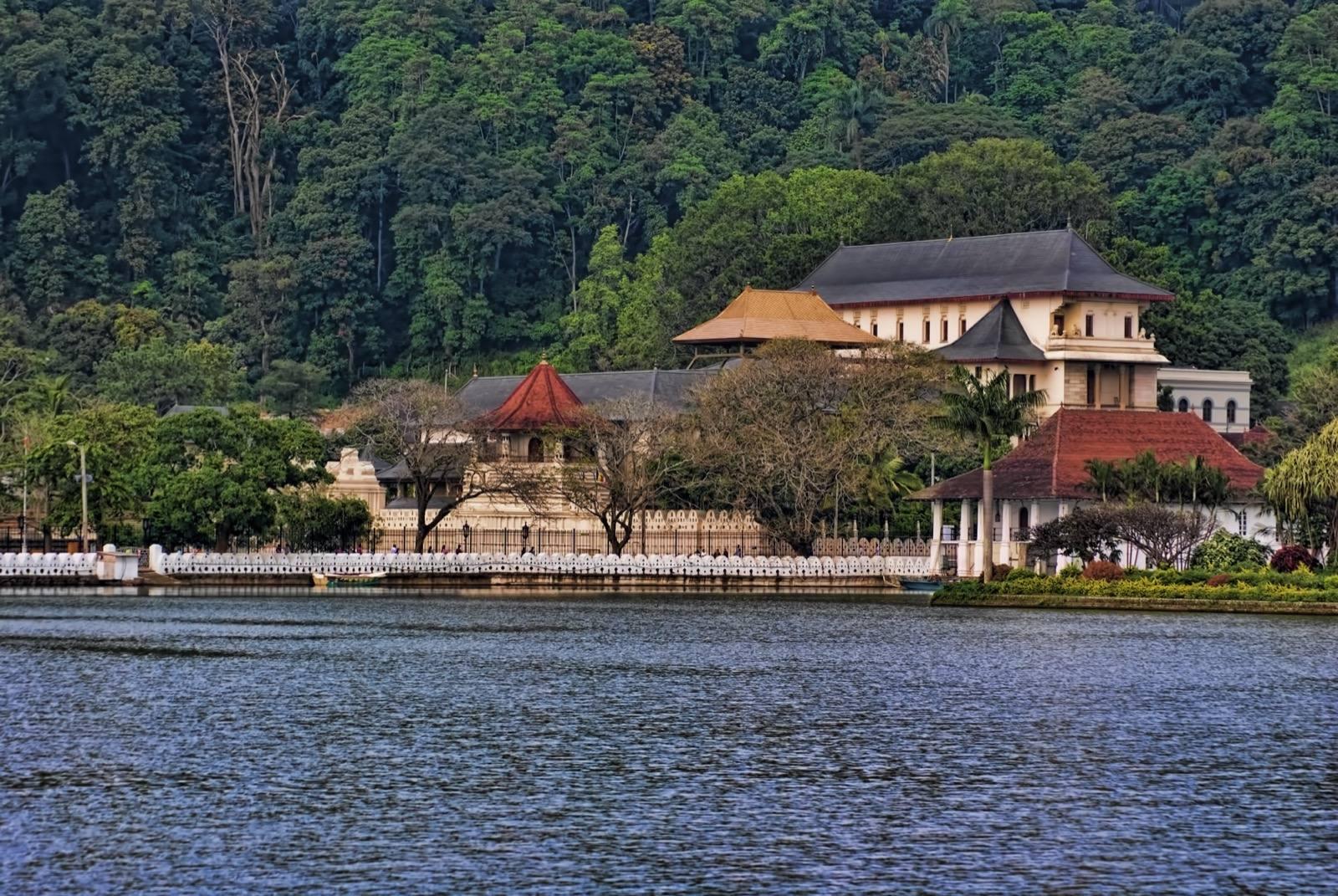 The Temple of the Sacred Tooth Relic in Kandy, seen across Kandy Lake against a forested hill