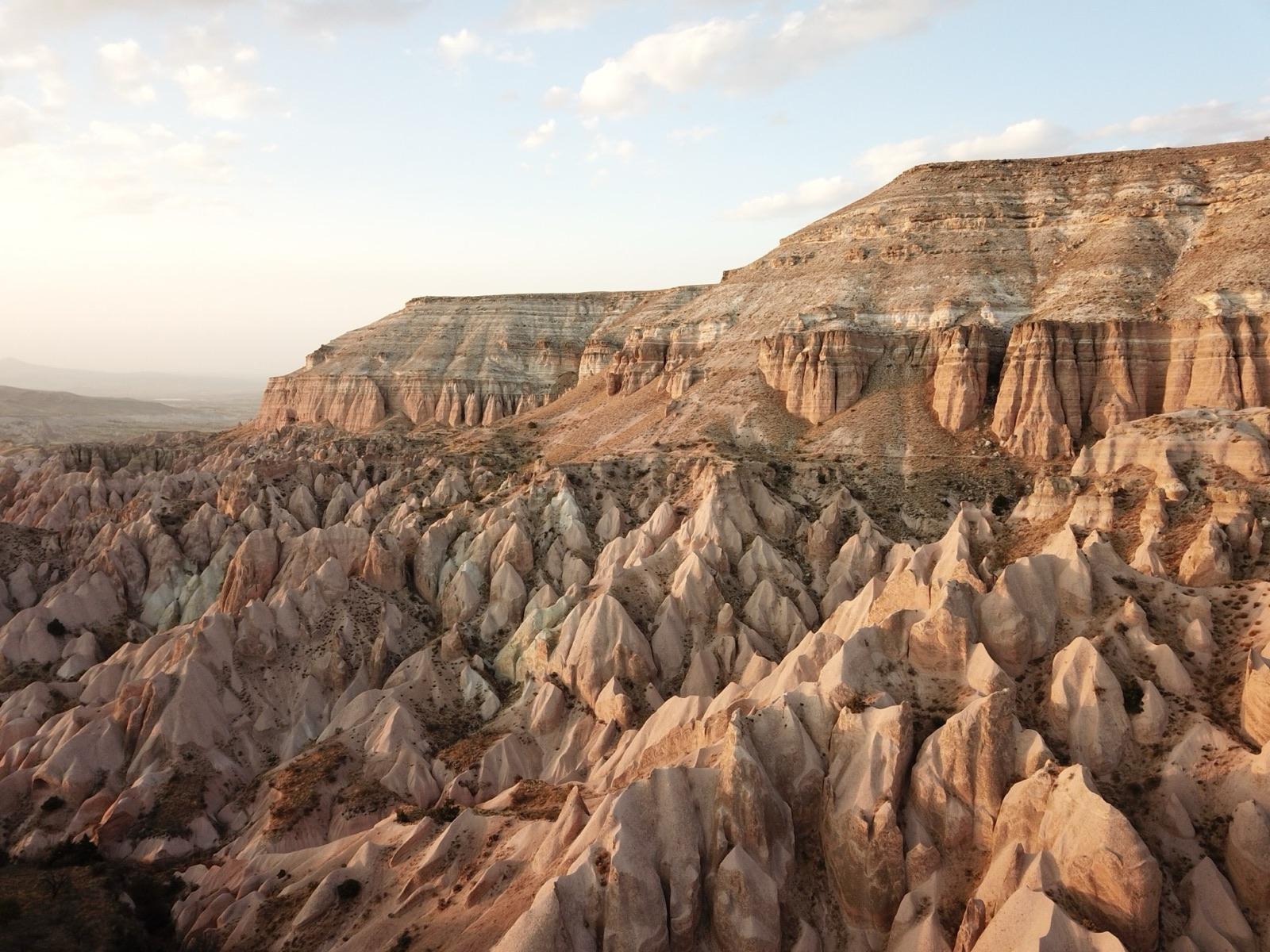 Pink and cream rock cones and a flat-topped ridge in the Red Valley, Cappadocia, in low evening light