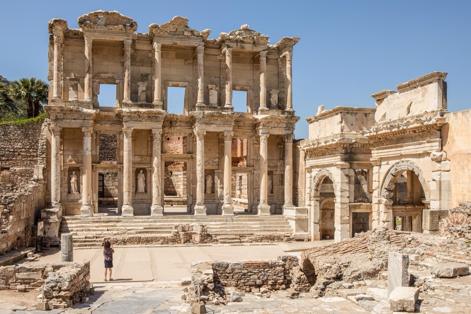 The two-storey marble facade of the Library of Celsus at Ephesus in morning light, with few visitors