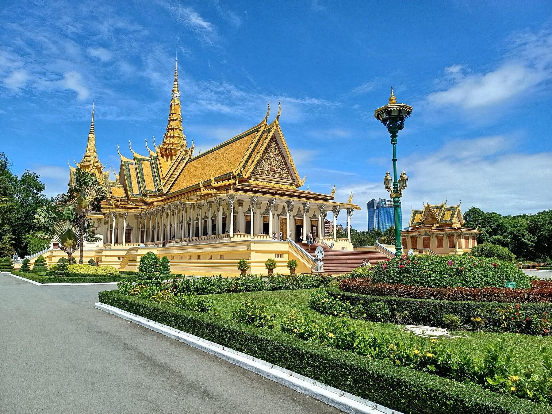 The golden roofs and spire of the Throne Hall at the Royal Palace in Phnom Penh above clipped gardens