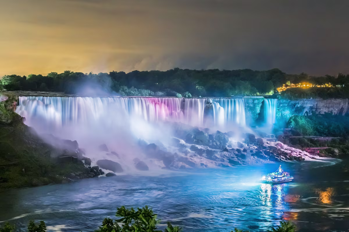 Niagara City Cruises boat with illuminated Niagara Falls at night.