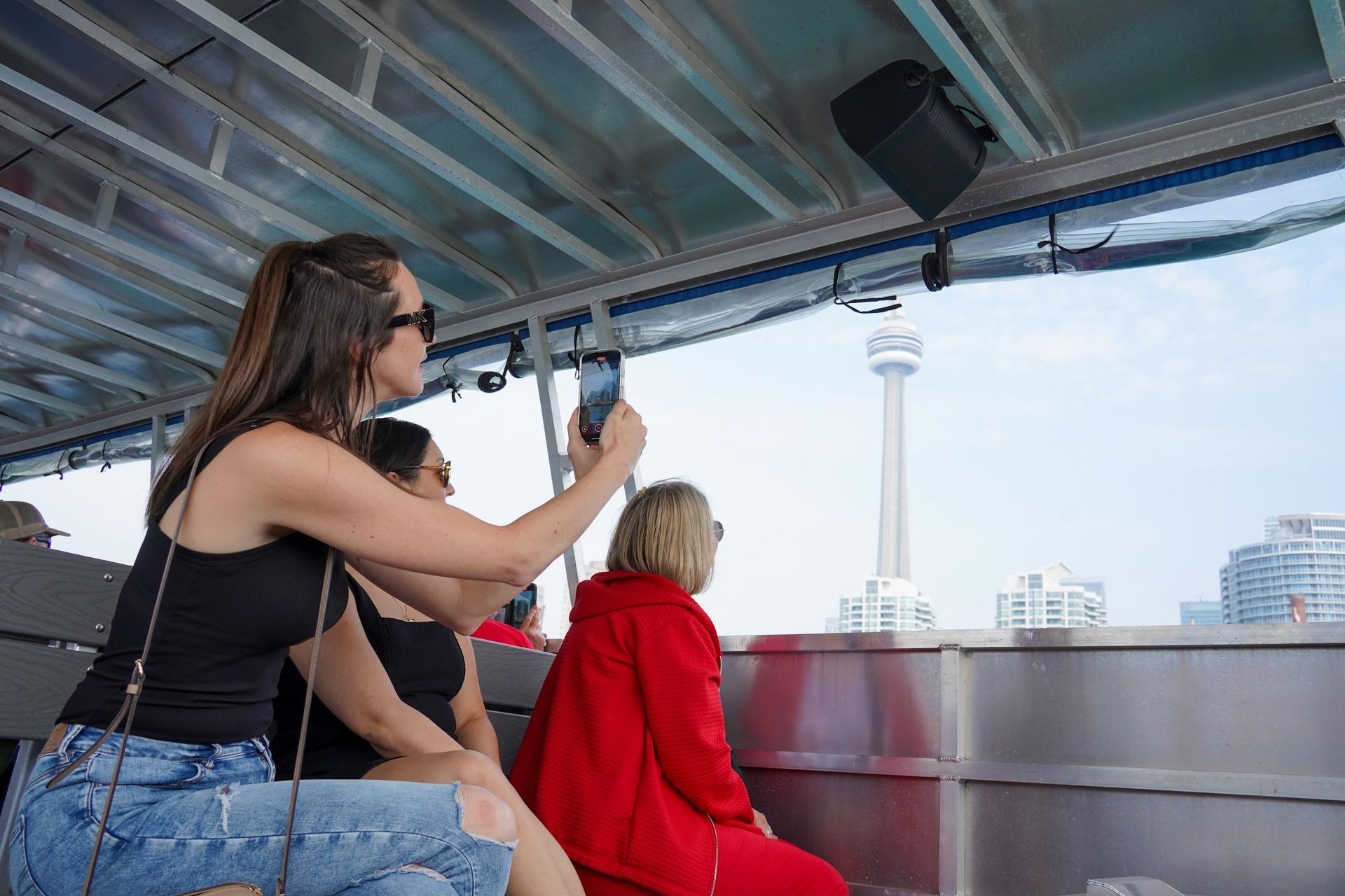 Guests on a boat look at the CN Tower and Toronto skyline