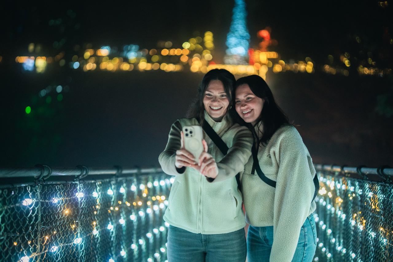 Guests take a selfie on the lit Capilano Suspension Bridge